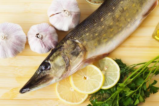 Raw pike with cooking ingredients on a cutting board