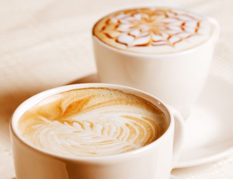 Coffee cup with artistic cream decoration, isolated on white background