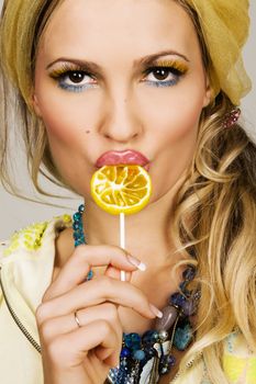 Gorgeous fashionable young woman holding a lemon candy