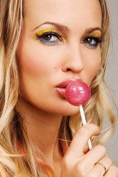 Beutiful woman with creative makeup holding a candy, closeup portrait