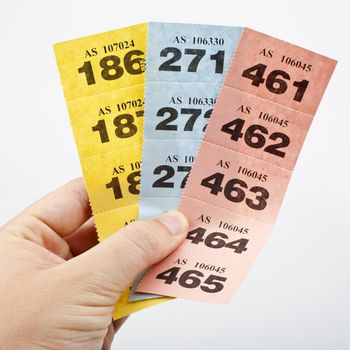Hand holding three strips of Raffle tickets.