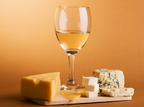 Wine and cheese over brown background still-life photo