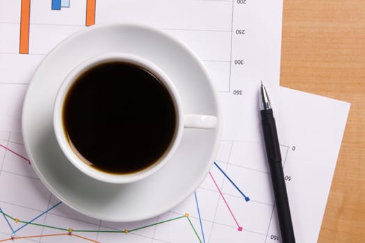 Cup of strong coffee over business diagrams, closeup soft focus photo