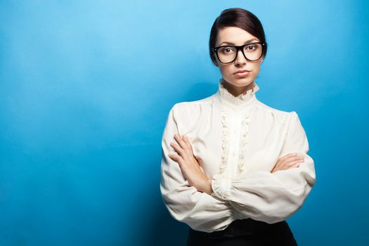 Strict woman in large glasses, blue background