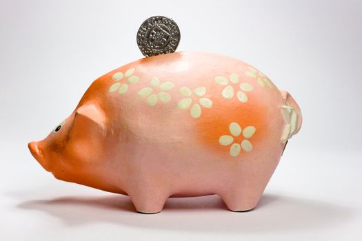 Ruddy piggy bank made of clay isolated on white background