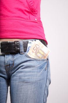 woman pink shirt detail with money in her pocket jeans