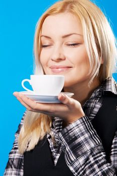 Young beautiful woman smelling coffee, blue background