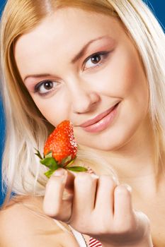 Beautiful girl tasting a strawberry, face portrait