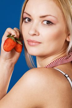 Beautiful girl tasting a strawberry, face portrait