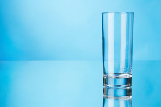 Empty glass on blue background, studio photo