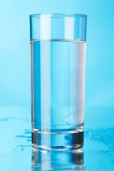 Glass of water on blue background, studio photo