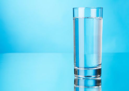 Glass of water on blue background, studio photo