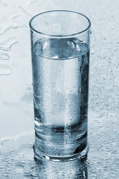 Glass of water on blue background, studio photo