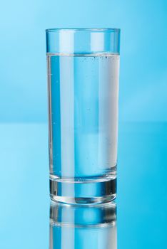 Glass of water on blue background, studio photo