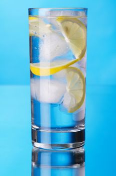 Glass of lemon ice water on blue background, studio photo