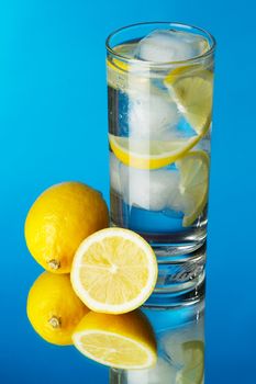 Glass of lemon ice water on blue background, studio photo