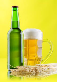 Beer mug and bottle on yellow background, studio photo