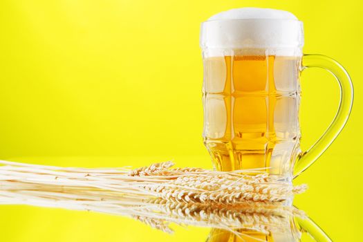 Beer mug and bottles on yellow background, studio photo