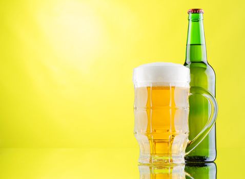 Beer mug and bottles on yellow background, studio photo