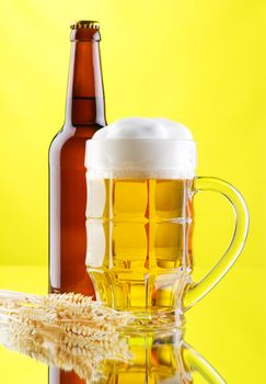 Beer mug and bottles on yellow background, studio photo