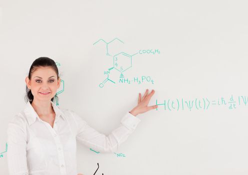 Female scientist looking at the camera while standing in front of a white board