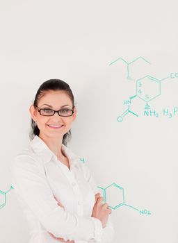 Dark-haired scientist woman looking at the camera while standing in front of a white board