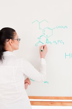 Scientist writing a formula on a white board in a laboratory