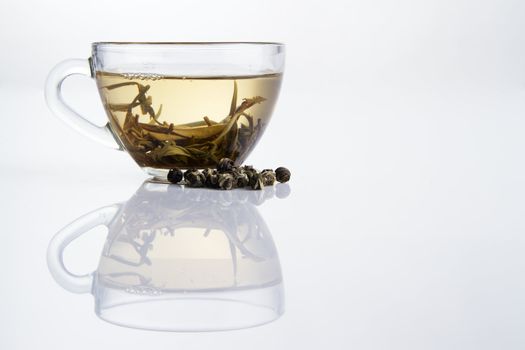 Glass cup of fresh white tea with dry tea granules