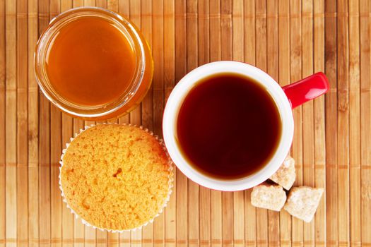 Cup of sweet tea with cake and honey