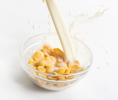 Milk flowing on a bowl of cornflakes