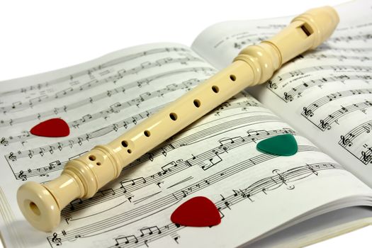 Flute (recorder) lying on notes sheet with several guitar pick-ups