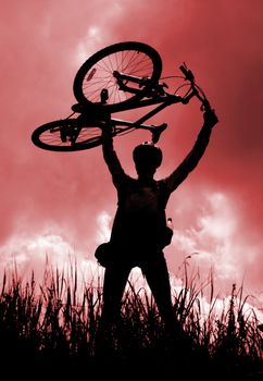 Silhouette of a biker holding his bicycle, red tint