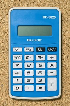 Closed up image of a blue calculator over a cork board background 