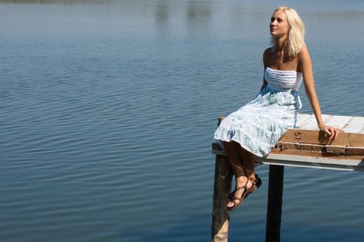 Girl sitting on a pier at the river shore