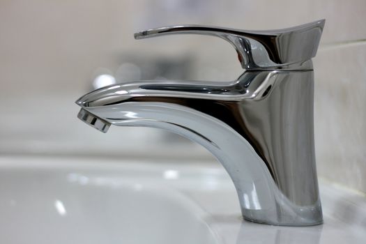 Modern chromed water faucet in a bathroom