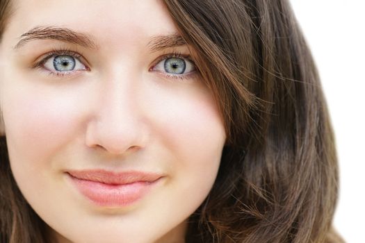 Portrait of a beautiful young woman, teenager or student with stunning light blue eyes and fare skin, looking surprised with her wide eyes and little smile.