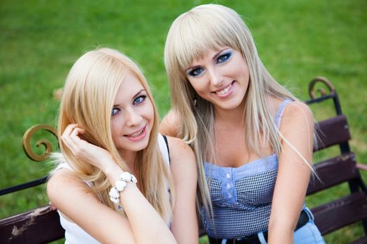 Two young pretty girl friends in a park