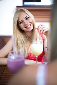 Pretty young woman drinking smoothie in a cafe