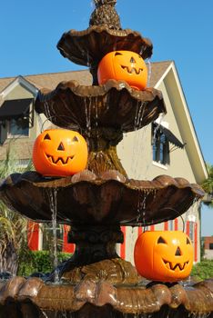 Three Halloween pumpkin pails on three tiers of a flowing fountain