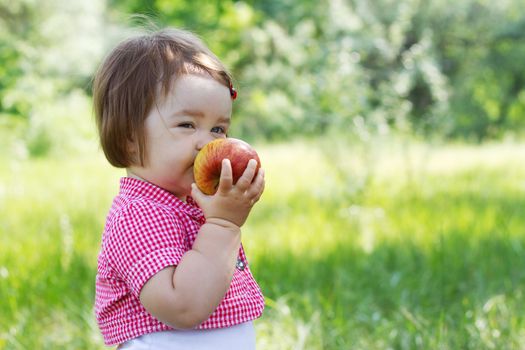 Cute child on a picnic, eating a big fresh apple