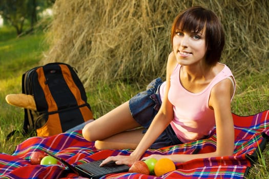 Lovely girl having a rest with laptop on picnic in the park 