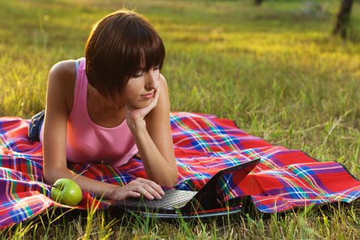 Lovely girl having a rest with laptop on picnic