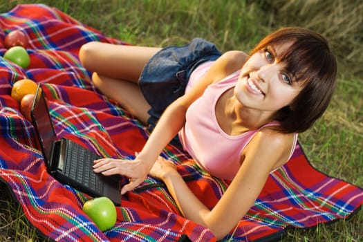 Lovely girl having a rest on picnic with laptop