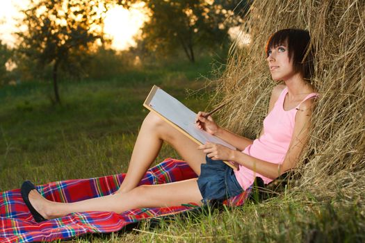 Lovely girl having rest and drawing in the park