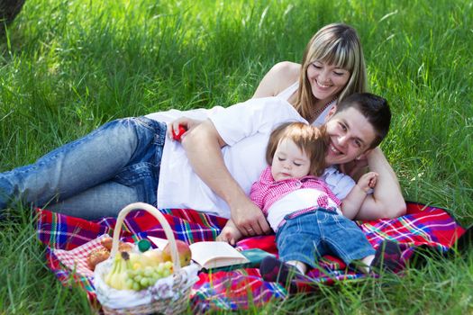 Young beautiful family of three on a picnic