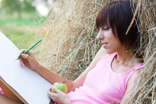 Lovely girl having rest and drawing in the park