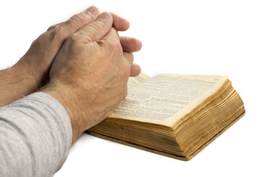man praying with hands on old bible