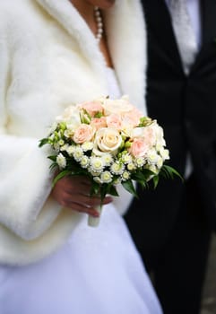 Bouquet of flowers on a background of a dress of the bride and a suit the groom.
