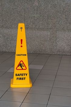 Caution wet floor sign on tiled floor with stone wall on background