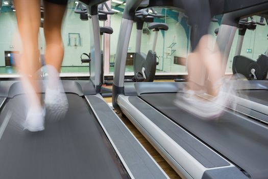 Two people running on treadmills side by side in the gym